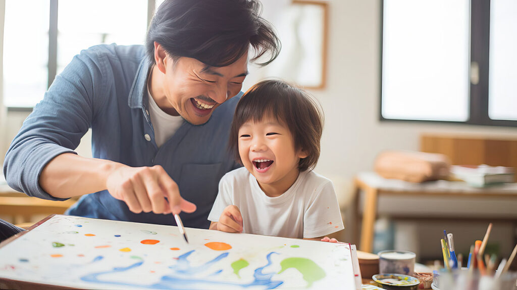 man sits and paints with his young son after learning about naturalistic intervention strategies