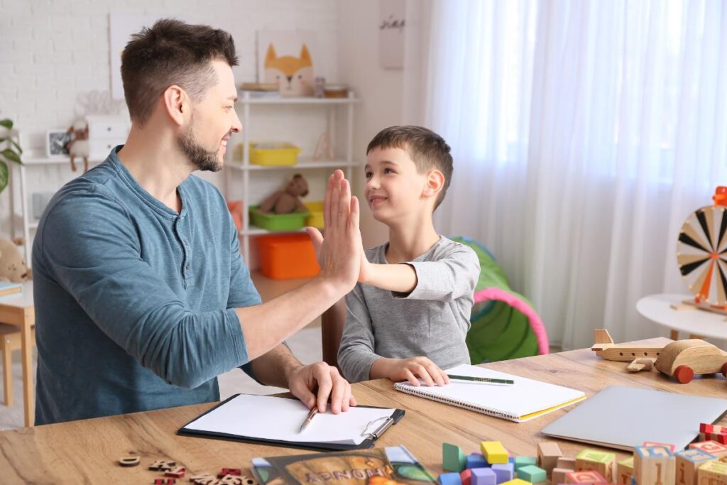 a male aba specialist works with a young child and high fives him after learning some interesting facts about autism