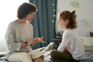 an adult woman sits with a young girl during the childs in home aba therapy