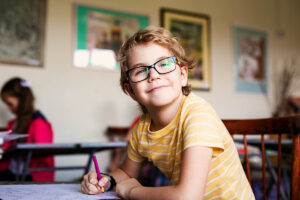 a boy with glasses smiles while attending a school for autistic children