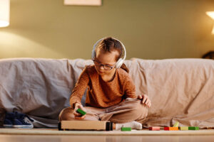 a young kid wearing headphones and sitting on a couch asks the question how to do aba therapy at home