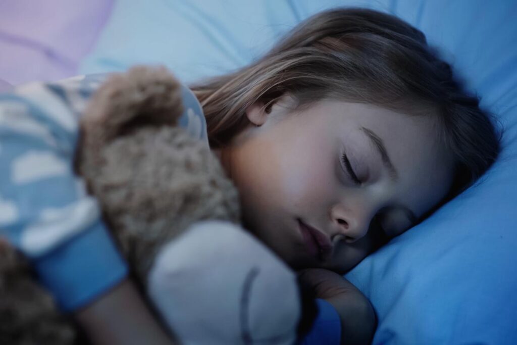 a young child sleeps with a teddy bear after being an autistic child who won't sleep alone