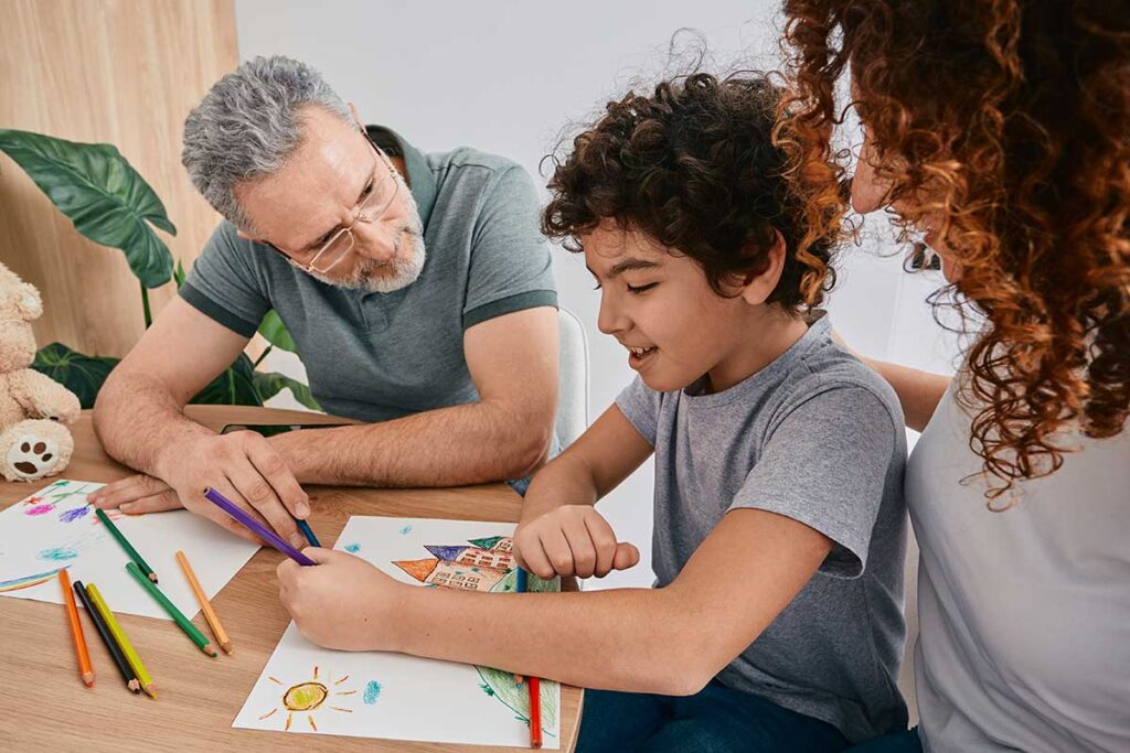 a child sits a table with a person who specializes in helping communication issues for children with autism