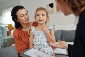 a mom and daughter sit with a specialist discussing calming strategies for autism