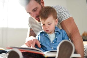 a father uses what he learns from parent training programs and reads a book with his toddler child