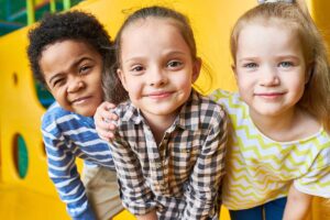 three young children sit together while smiling and learning about self soothing behaviors